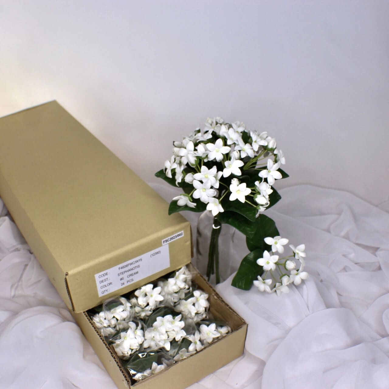 artificial Stephanotis placed in glass transparent glass and in box