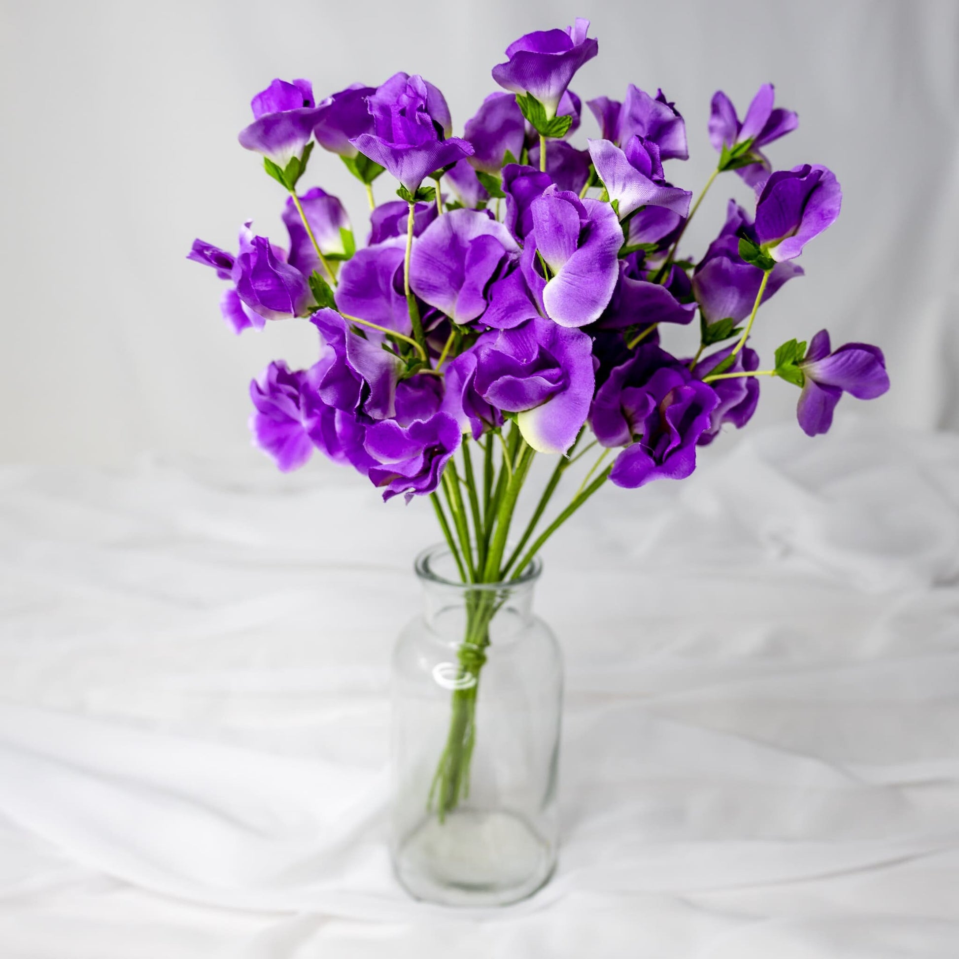 artificial Mauve Sweet Pea flowers in glass vase