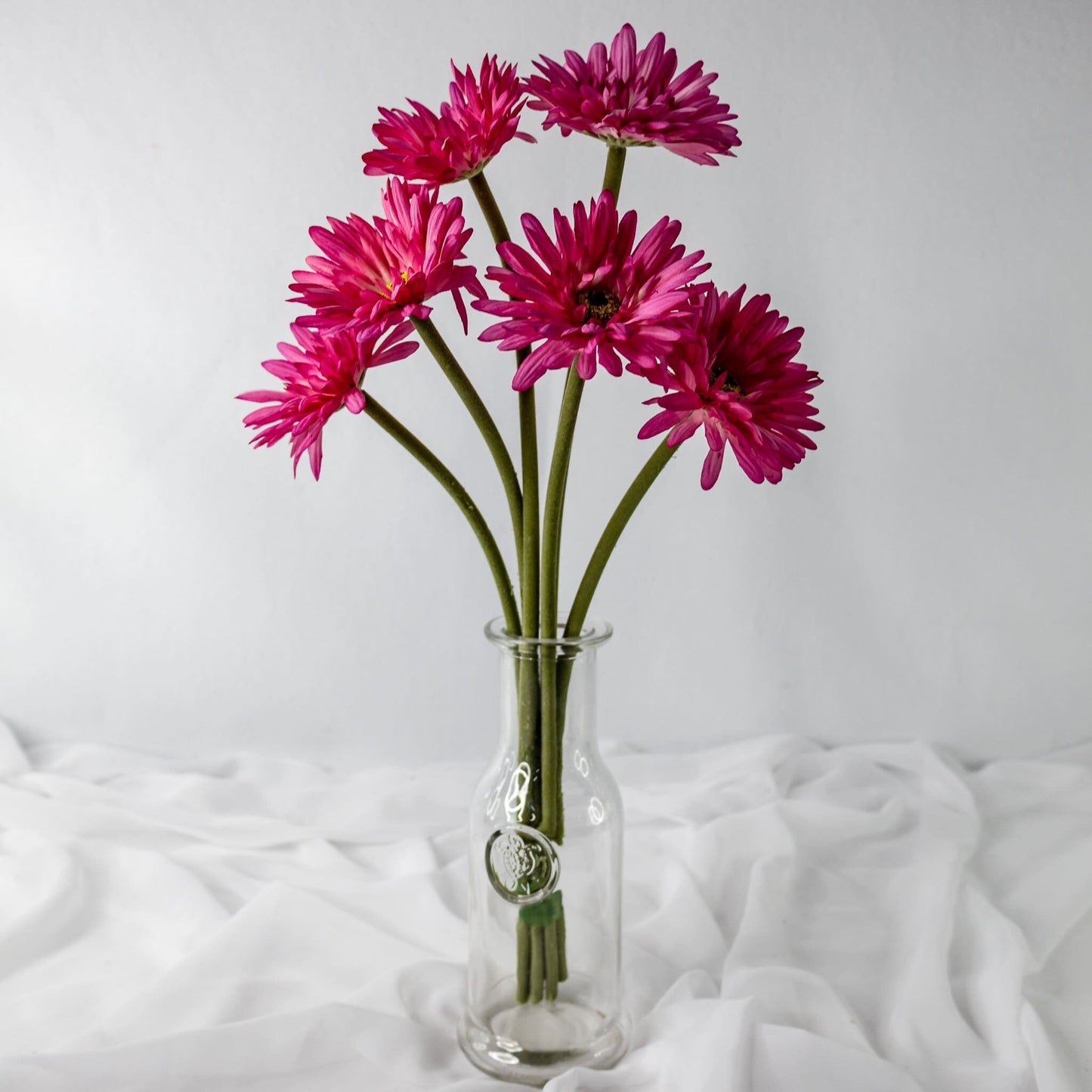 Artificial Pink Gerbera flowers in clear glass vase