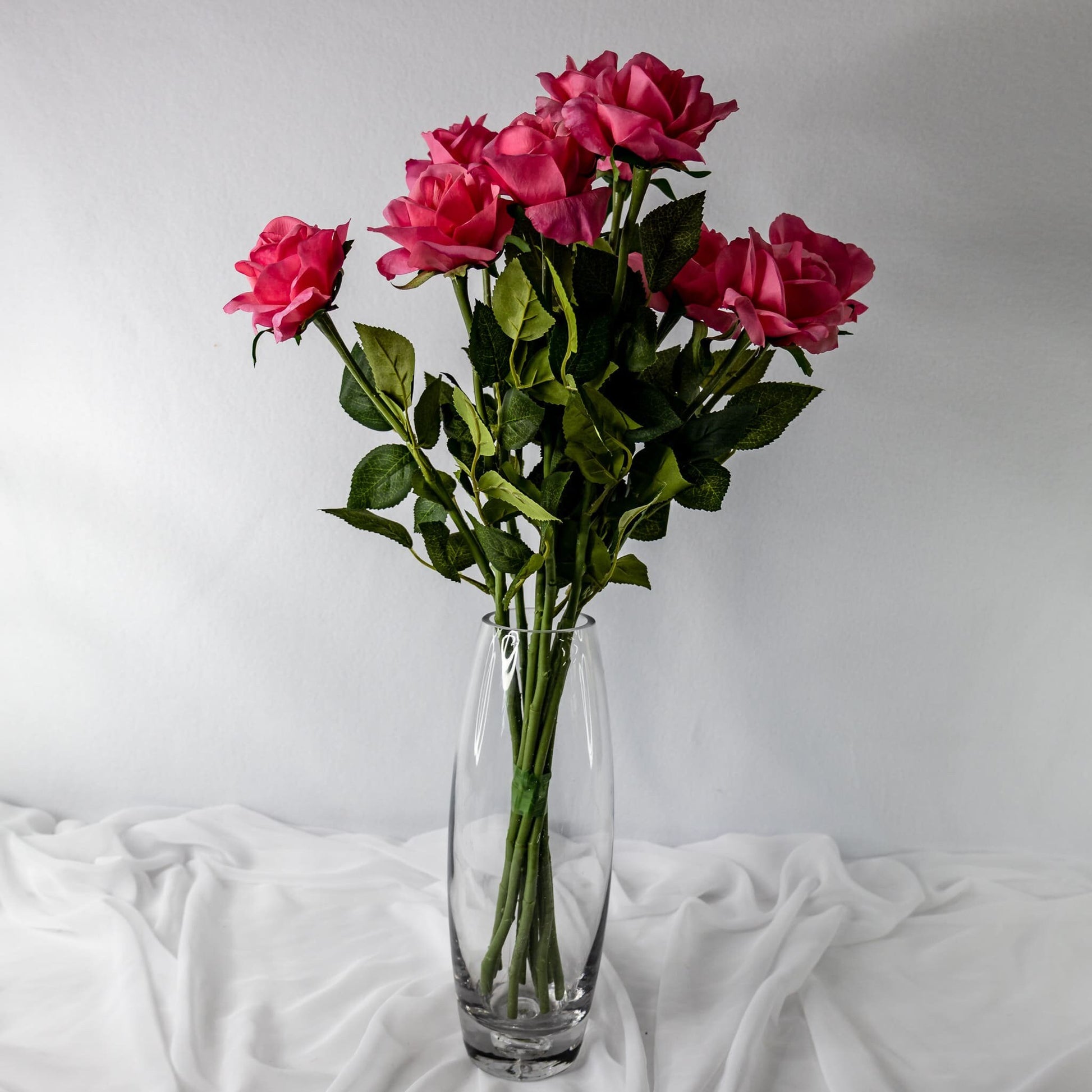 artificial pink real touch open bloom roses placed in glass transparent vase