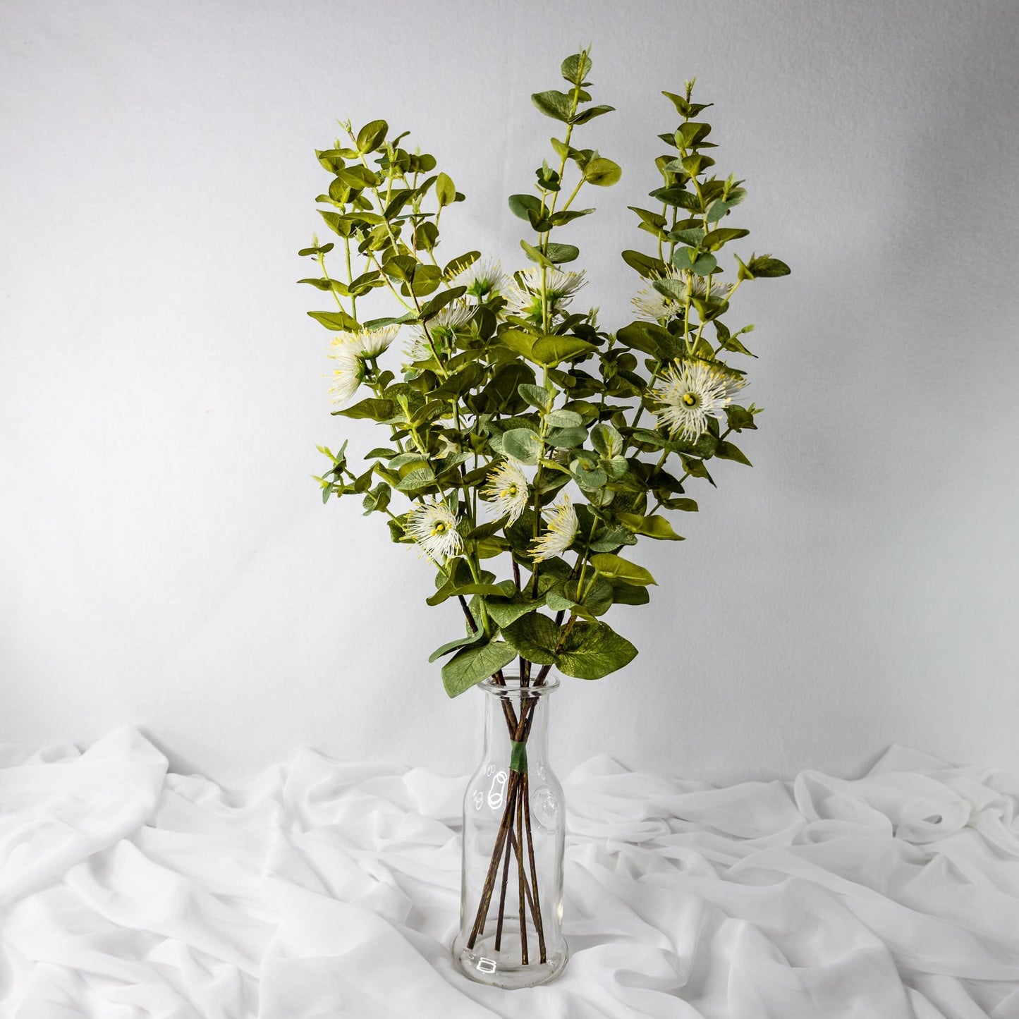 artificial white flowering gum blossom placed in transparent glass vase