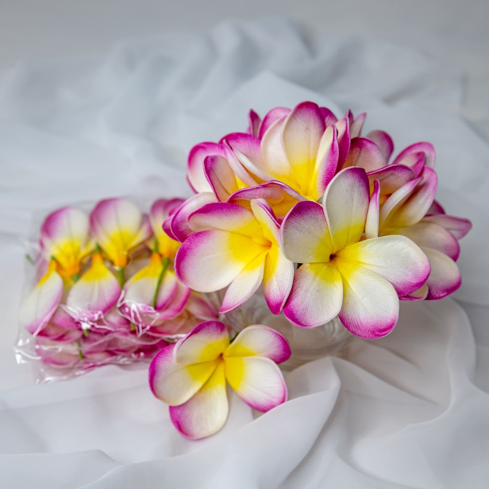 artificial white fuchsia frangipani flowerhead in clear glass vase