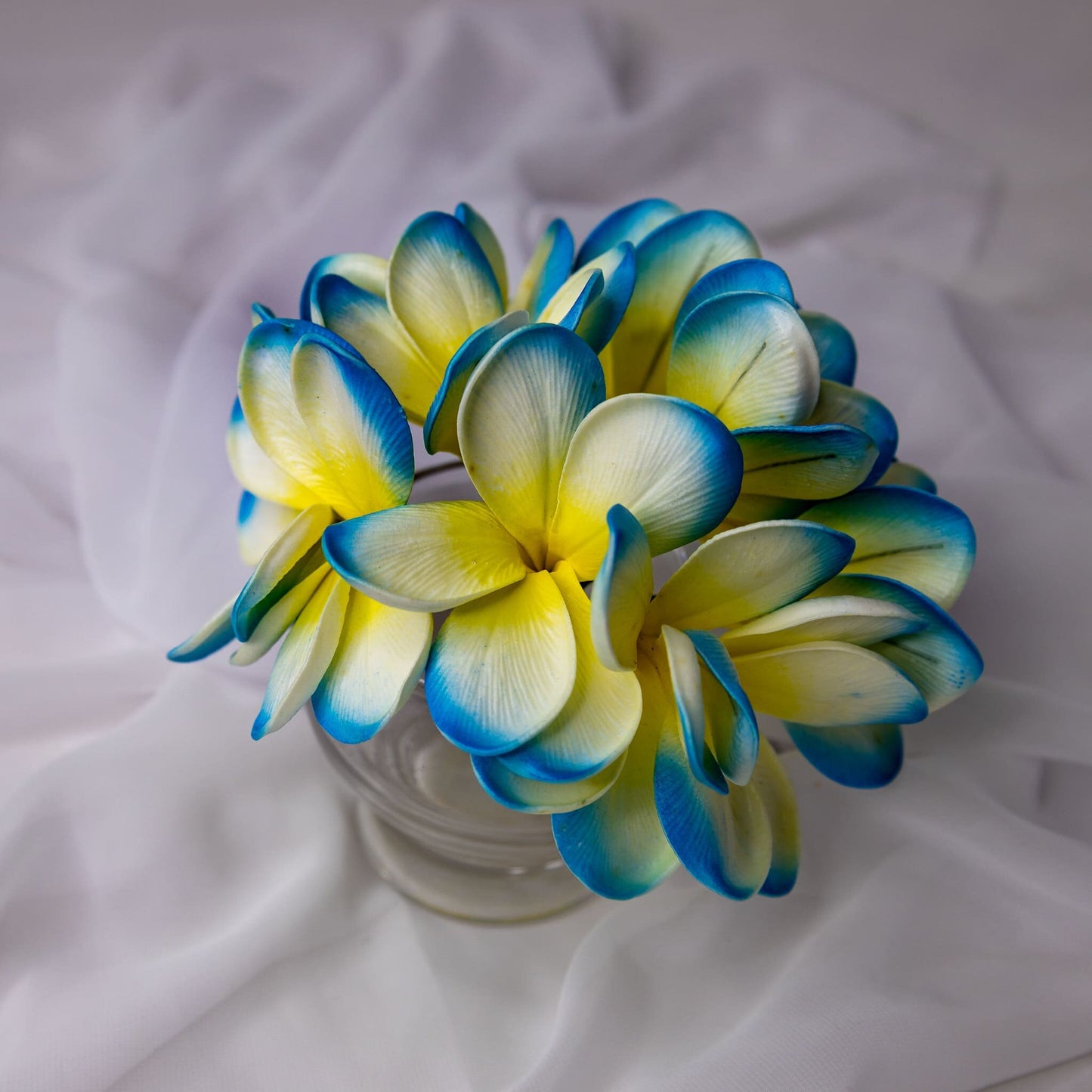 artificial skye blue frangipani flowers placed in transparent glass vase