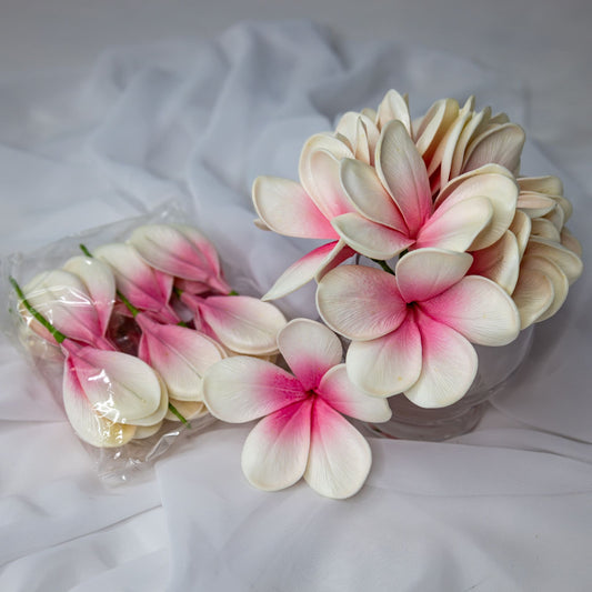 artificial white pink frangipani flowers placed in transparent glass vase