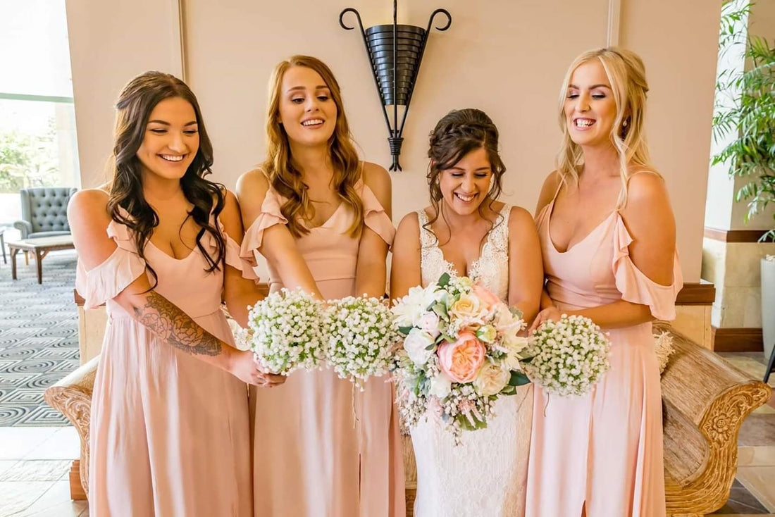 A bride and wedding bridesmaids holding artificial flowers
