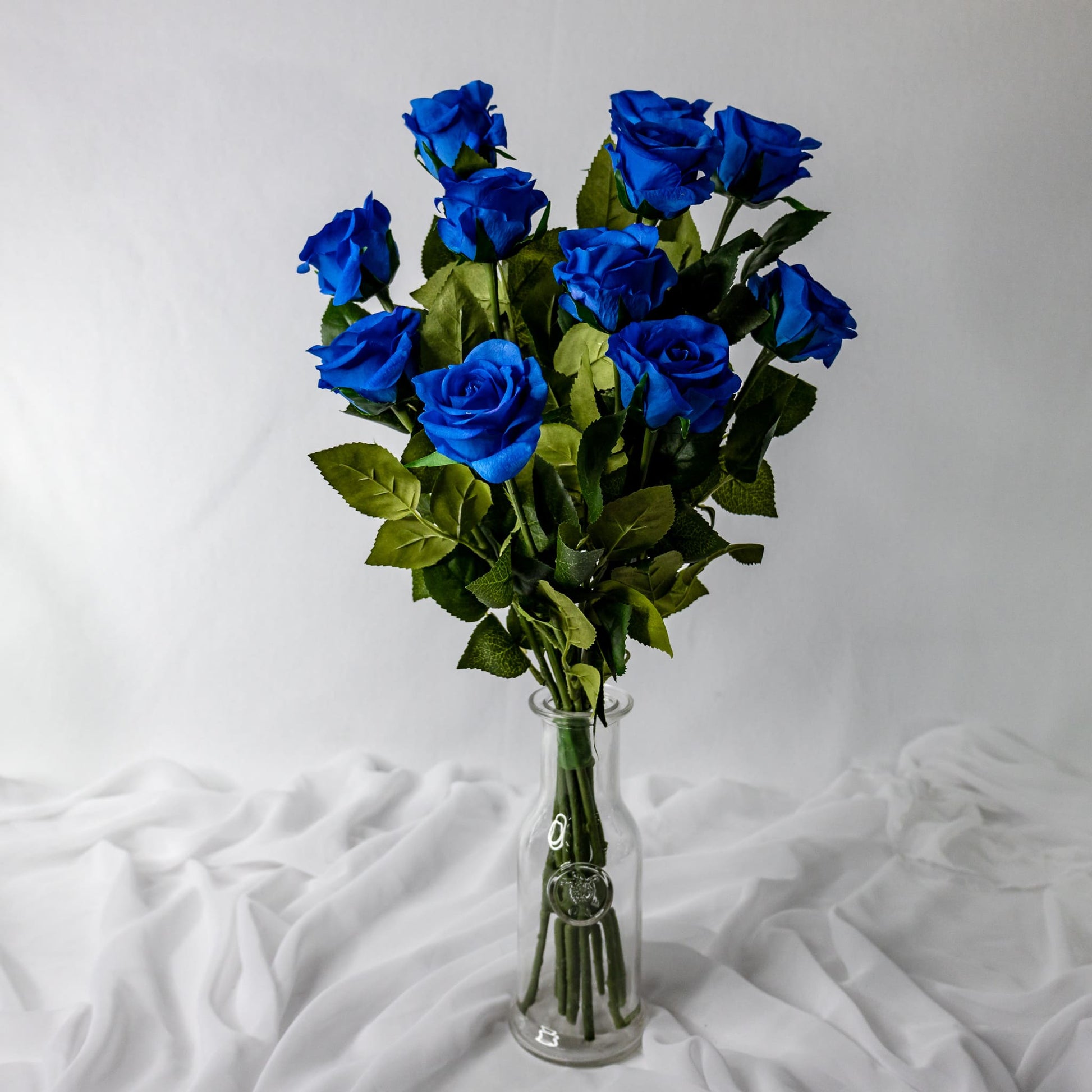 artificial deep blue roses in half bloom placed in clear glass vase