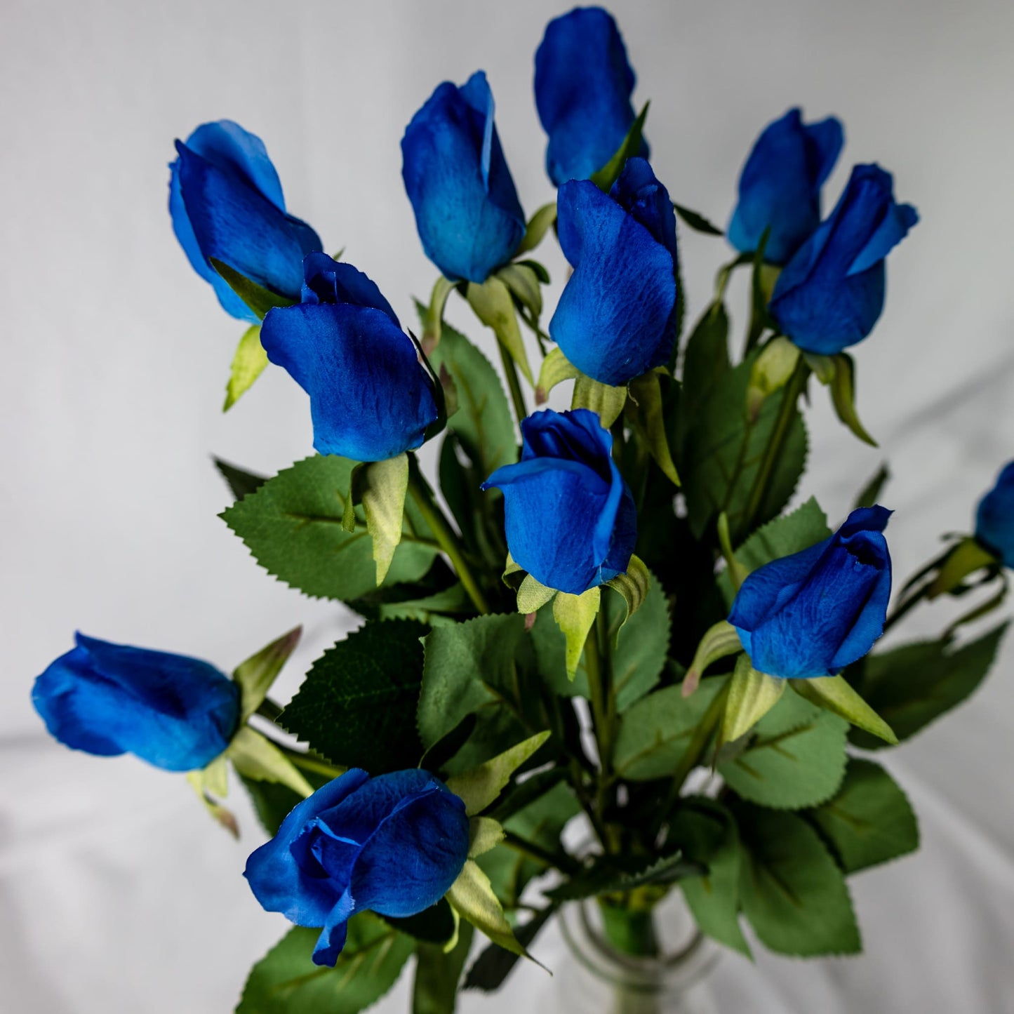 artificial deep blue rosebuds placed in clear glass vase top view