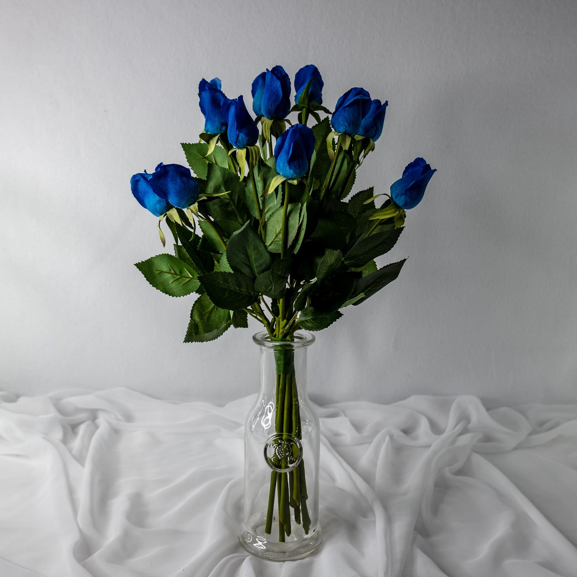 artificial deep blue rose buds placed in clear glass vase