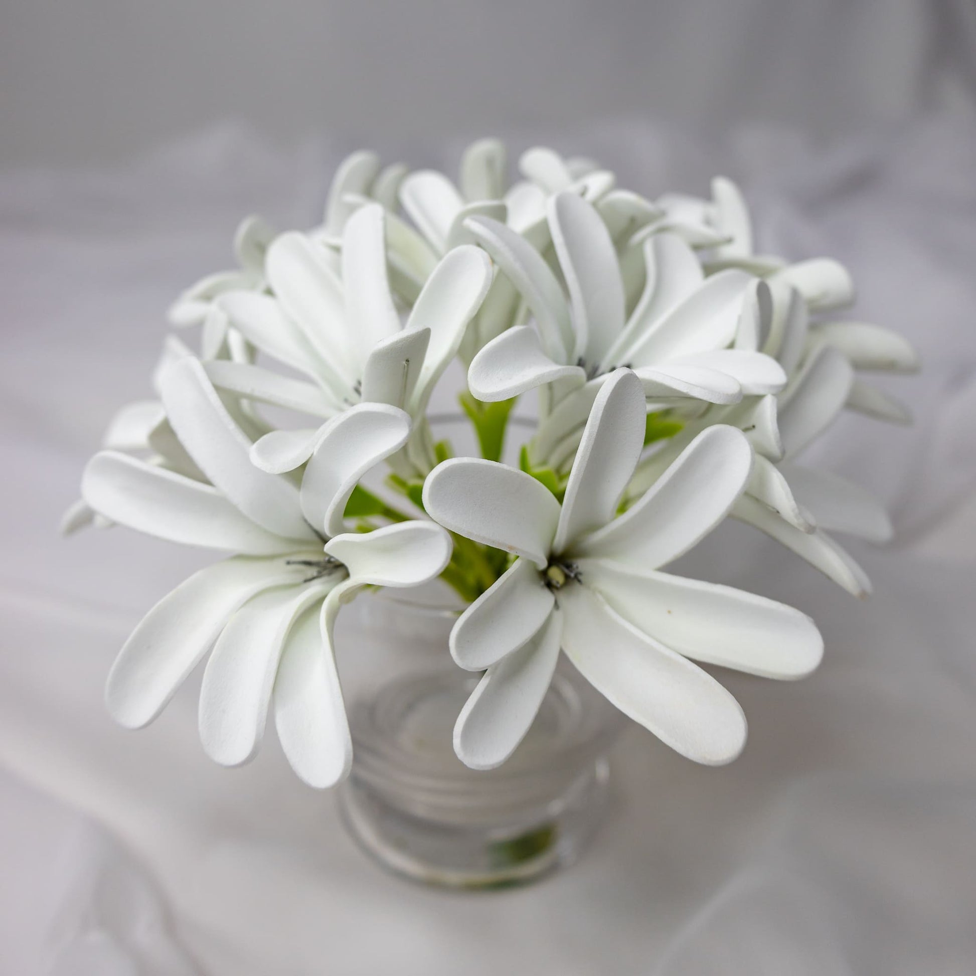 artificial tahitian gardenia flowers placed in transparent glass vase