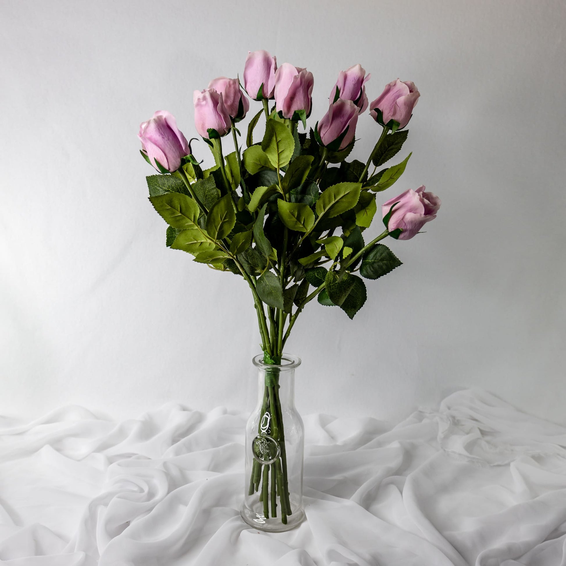 artificial vintage lilac roses placed in transparent glass vase