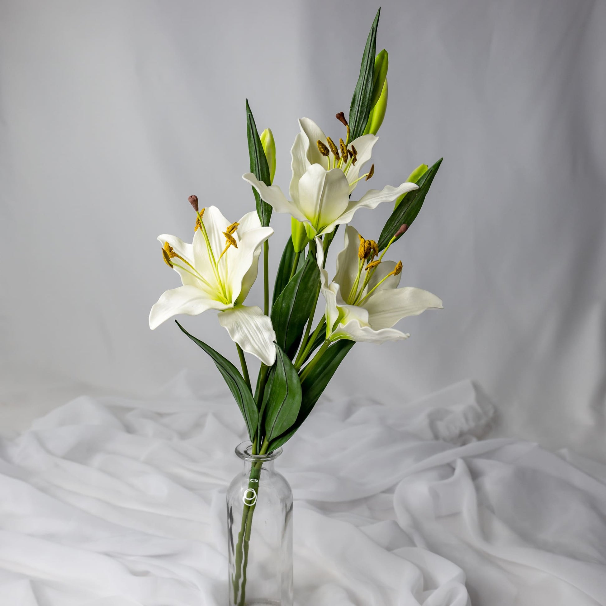 artificial small white asiatic lilies placed in transparent glass vase