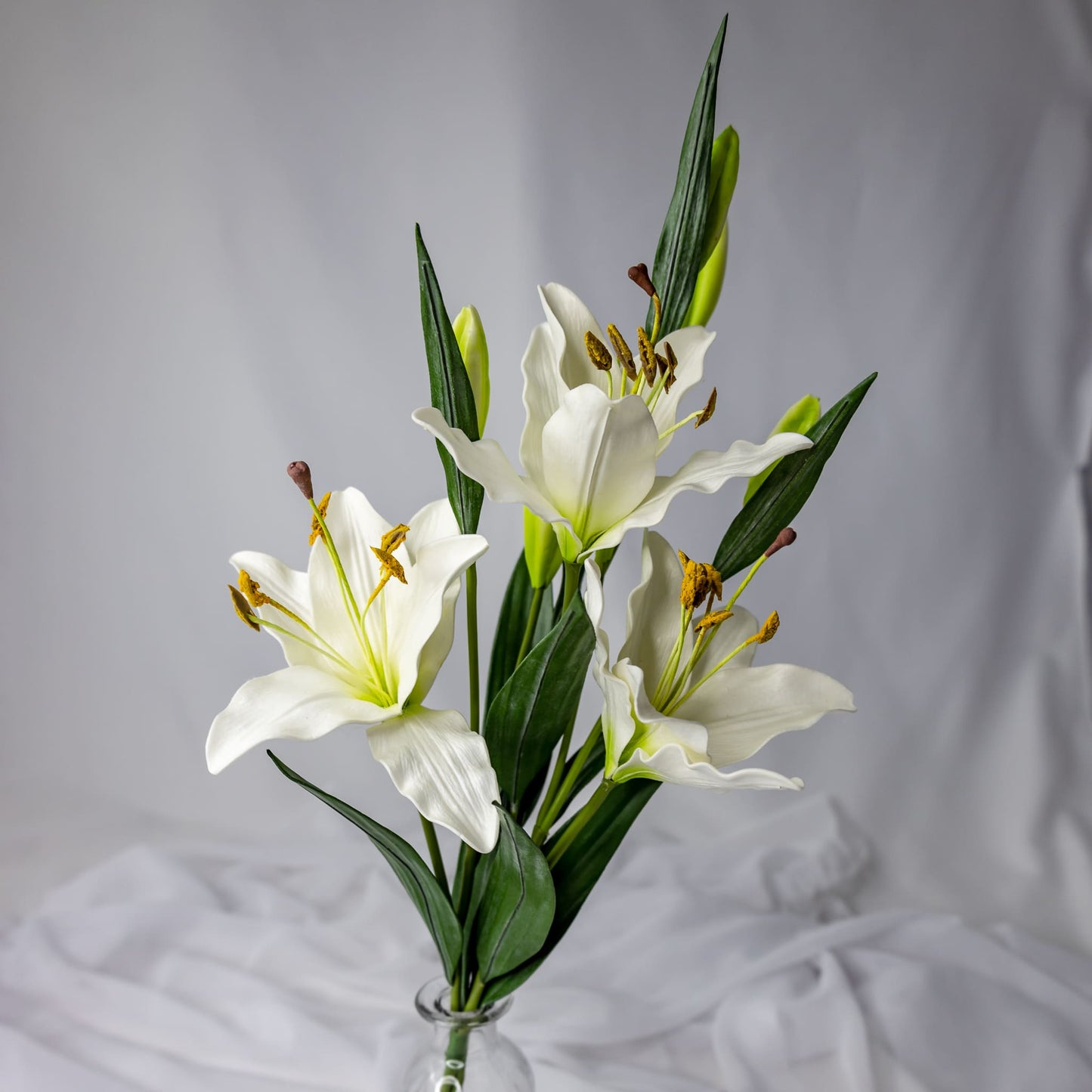 artificial small white asiatic lilies placed in transparent glass vase