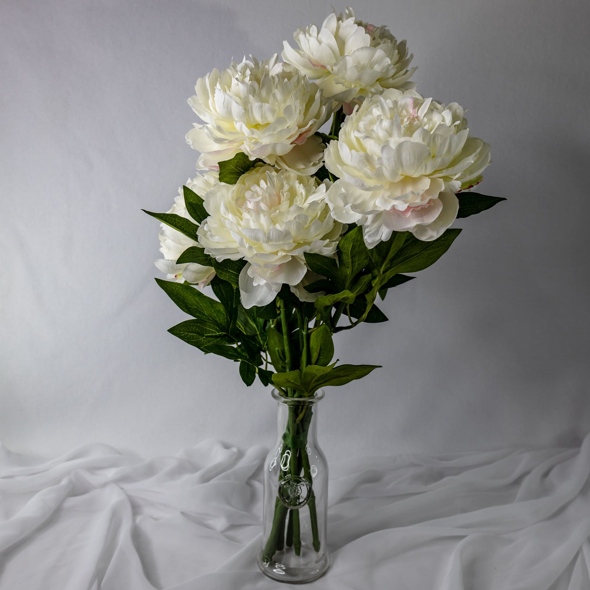 artificial large white peonies placed in transparent glass vase