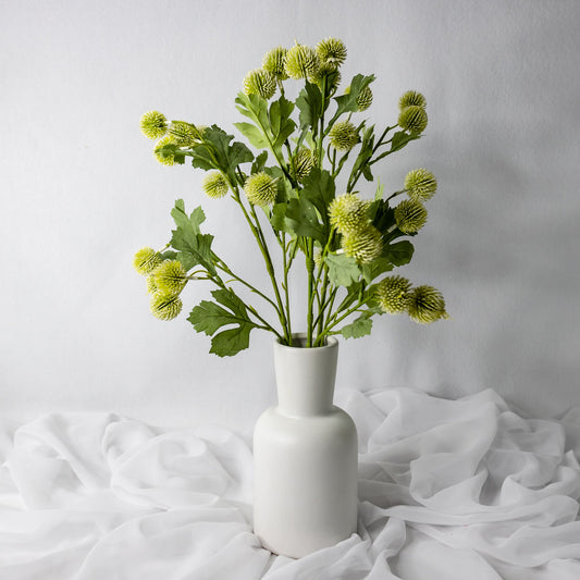 artificial white pom pom spray placed in white vase