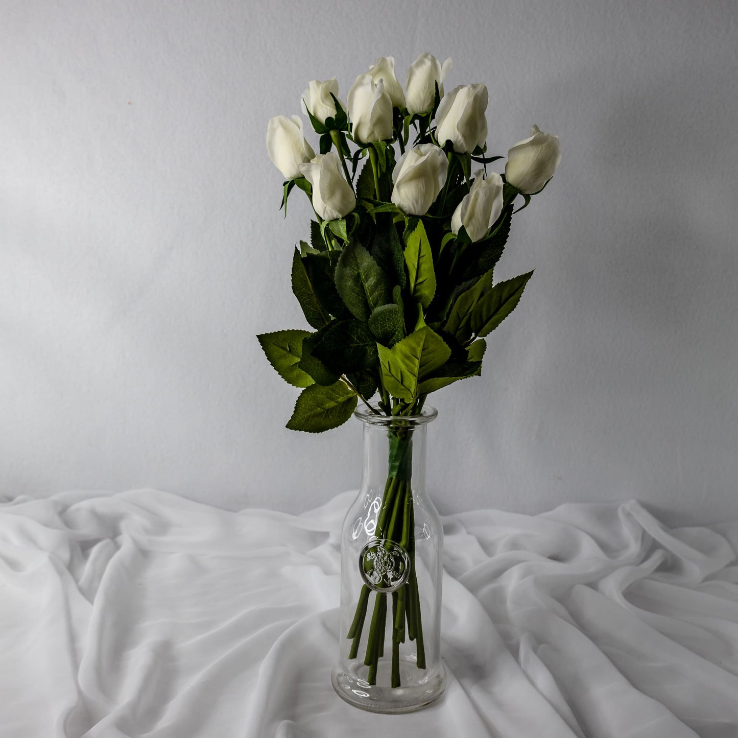artificial white real touch rose buds placed transparent glass vase