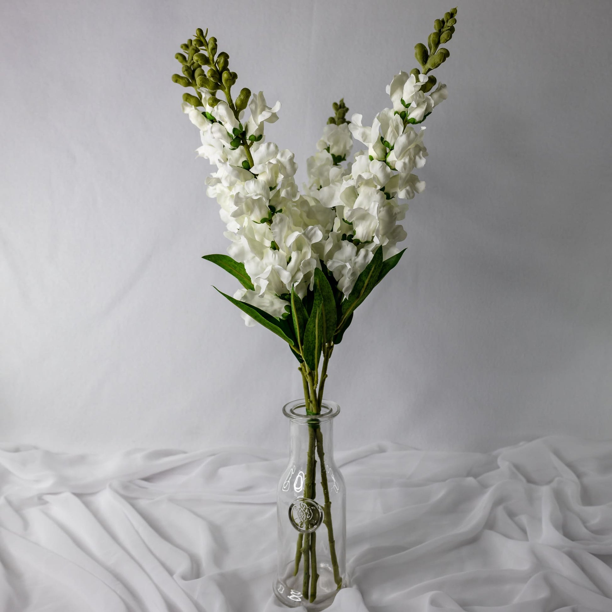 artificial white snap dragons in glass vase