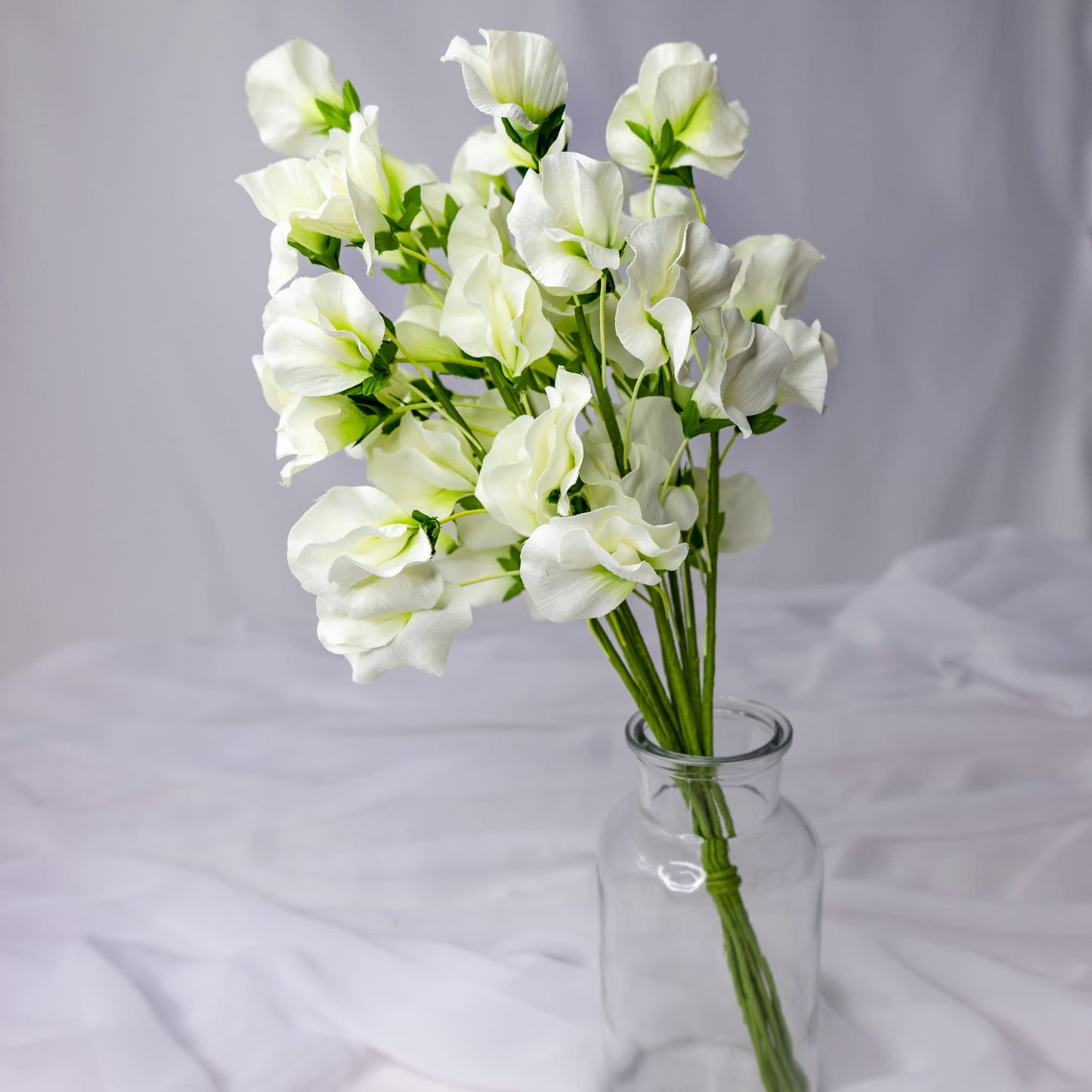 artificial white sweet pea placed in transparent glass vase