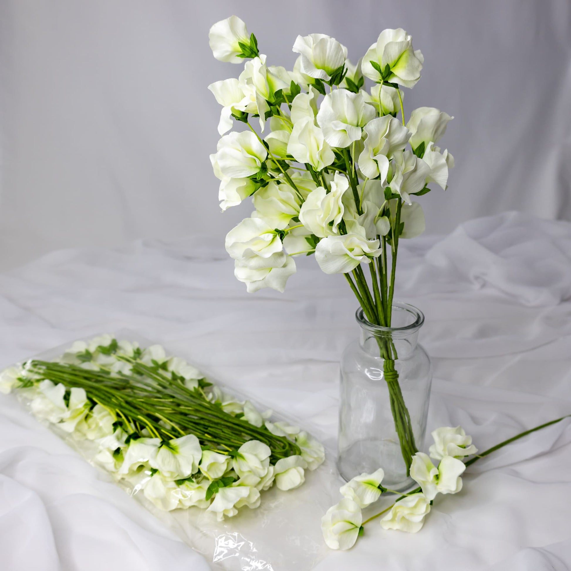 artificial white sweet pea placed in transparent glass vase