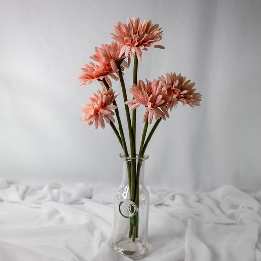 Artificial pale pink gerberas in clear glass vase