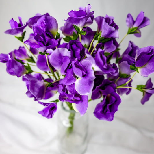 artificial Mauve Sweet Pea flowers in clear glass vase top view