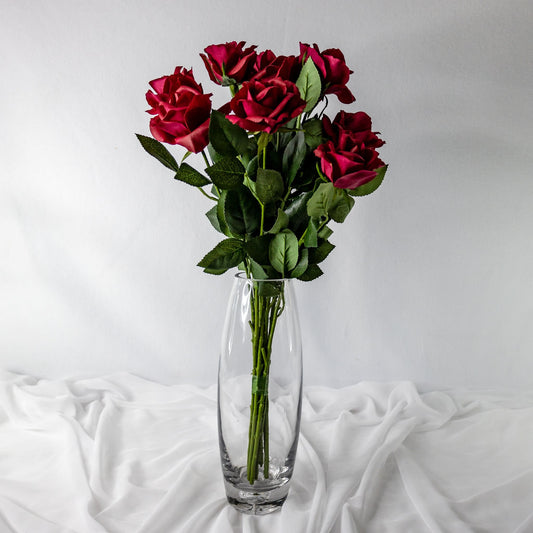 artificial red open bloom roses placed in glass transparent vase