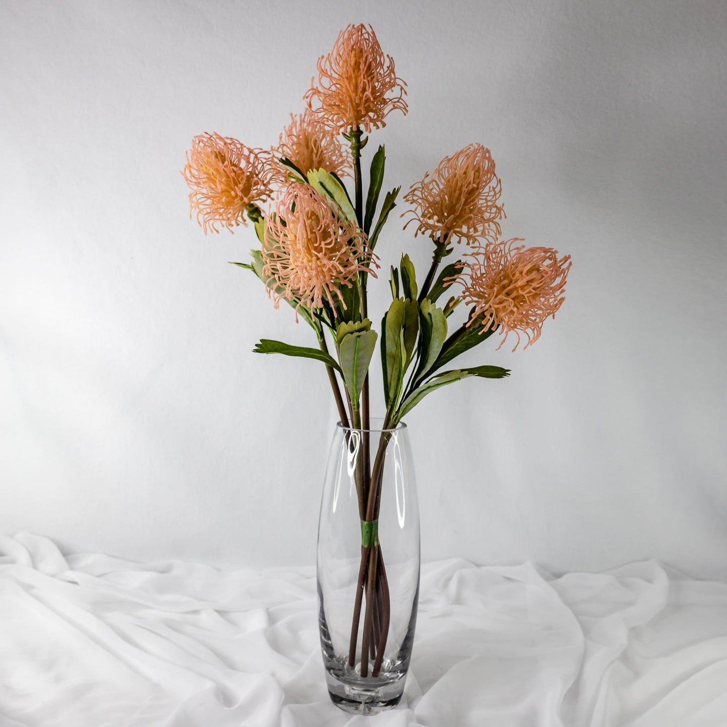 artificial pink leucospermum placed in transparent glass vase