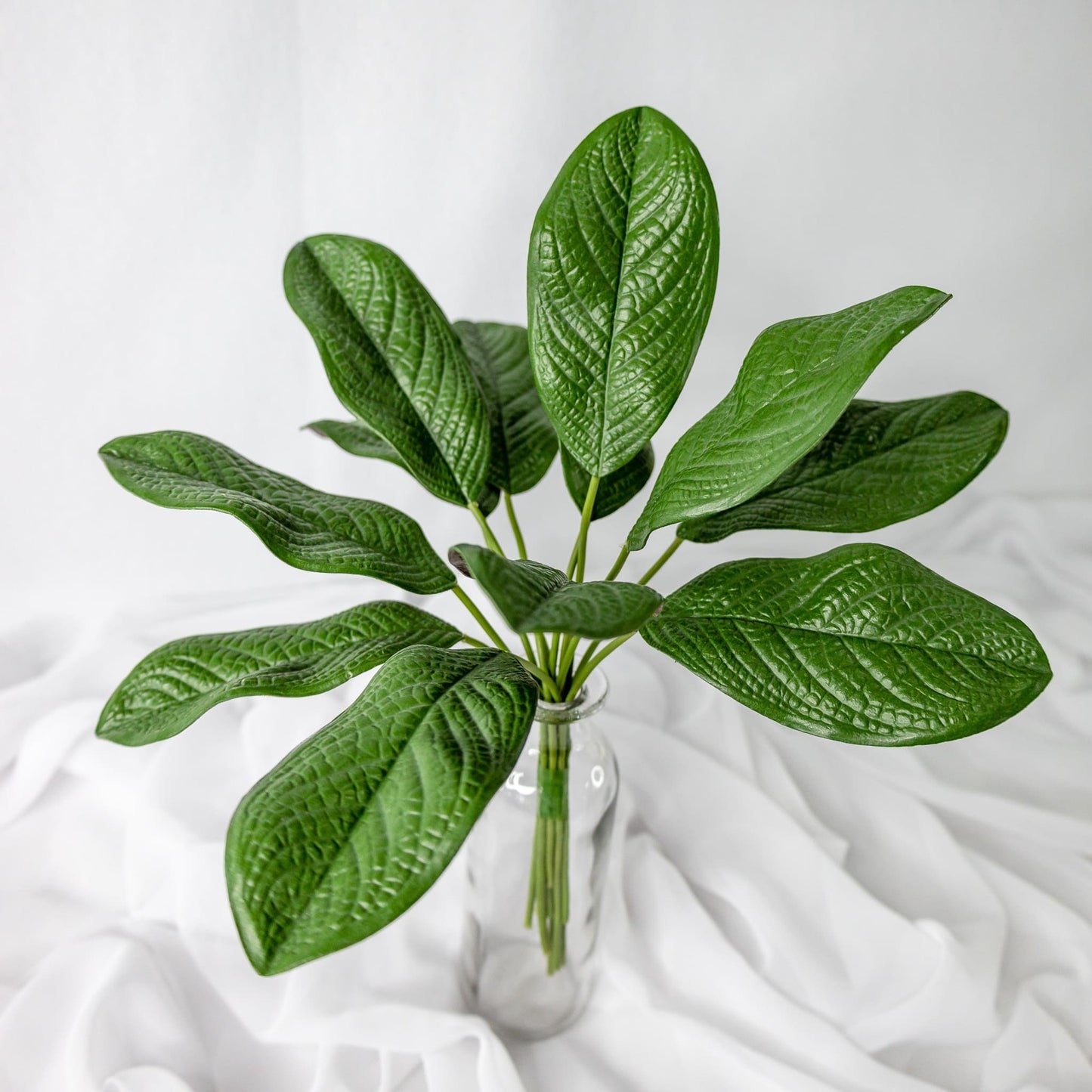 artificial small magnolia leaves placed in transparent glass vase