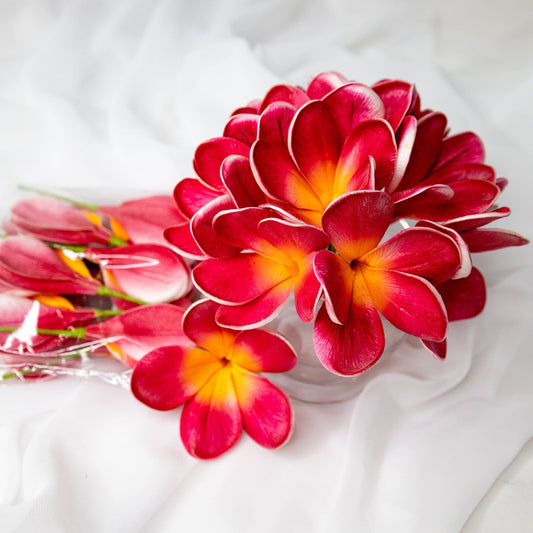 artificial passion frangipani flowers placed in transparent glass vase