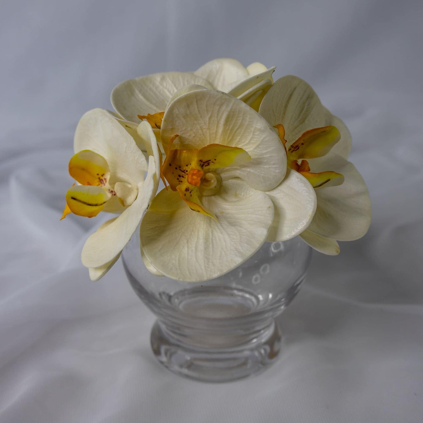 artificial white and yellow phalaenopsis in clear glass vase