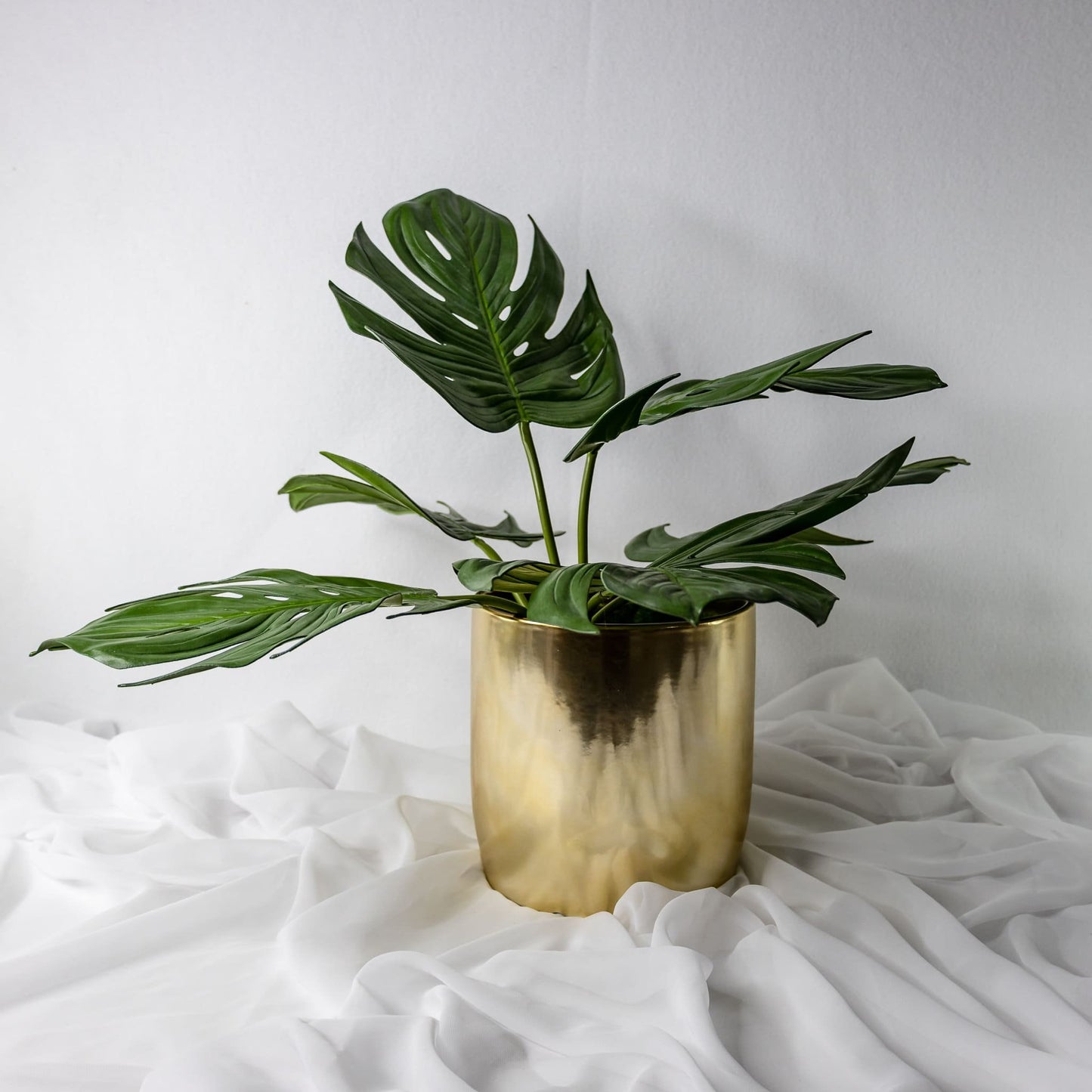 artificial small monstera leaves placed in gold vase